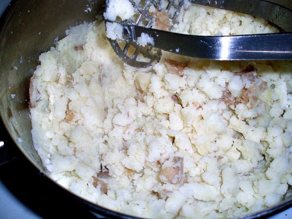 Mahing potatoes with potato masher in pot