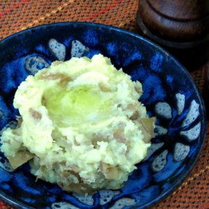 Blue bowl of mashed potatoes with peel and butter