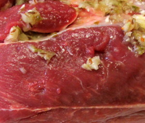 Stuffing seasoning into slits in pork shoulder, so the flavor will permeate the meat. www.inhabitedkitchen.com