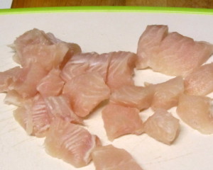 Slicing a fillet of white fish into bite sized pieces - www.inhabitedkitchen.com