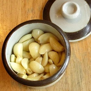 Peeled garlic cloves in baking dish, with oil. 