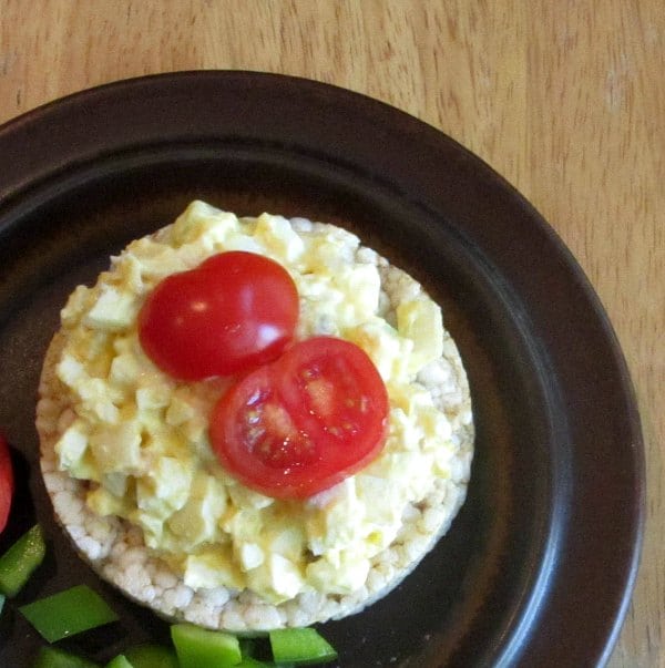 Egg salad on rice cake with tomatoes.