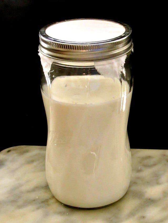 Milk being cultured with kefir grains, in a jar.