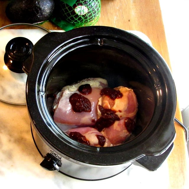 Slow cooker with raw boned chicken thighs and chipotle puree.