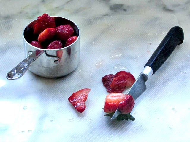 Cutting strawberries to discard unripe parts.