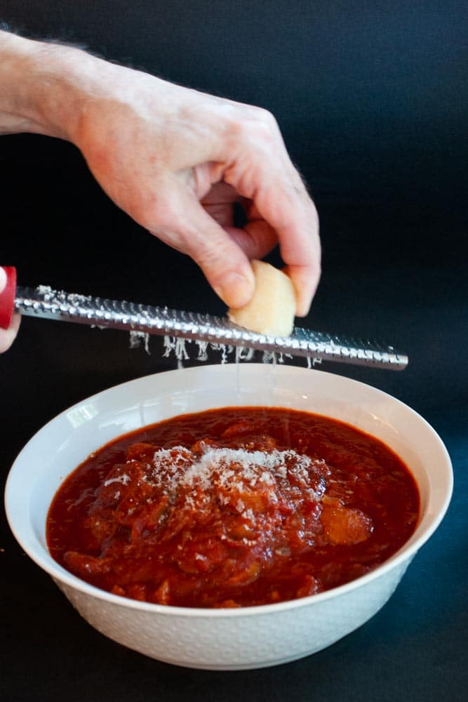 Grating cheese over pasta sauce